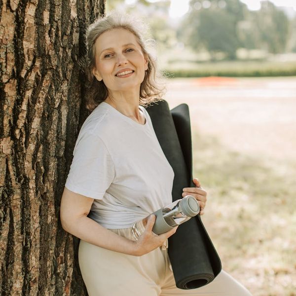 Person smiling peacefully outdoors, representing overall well-being.
